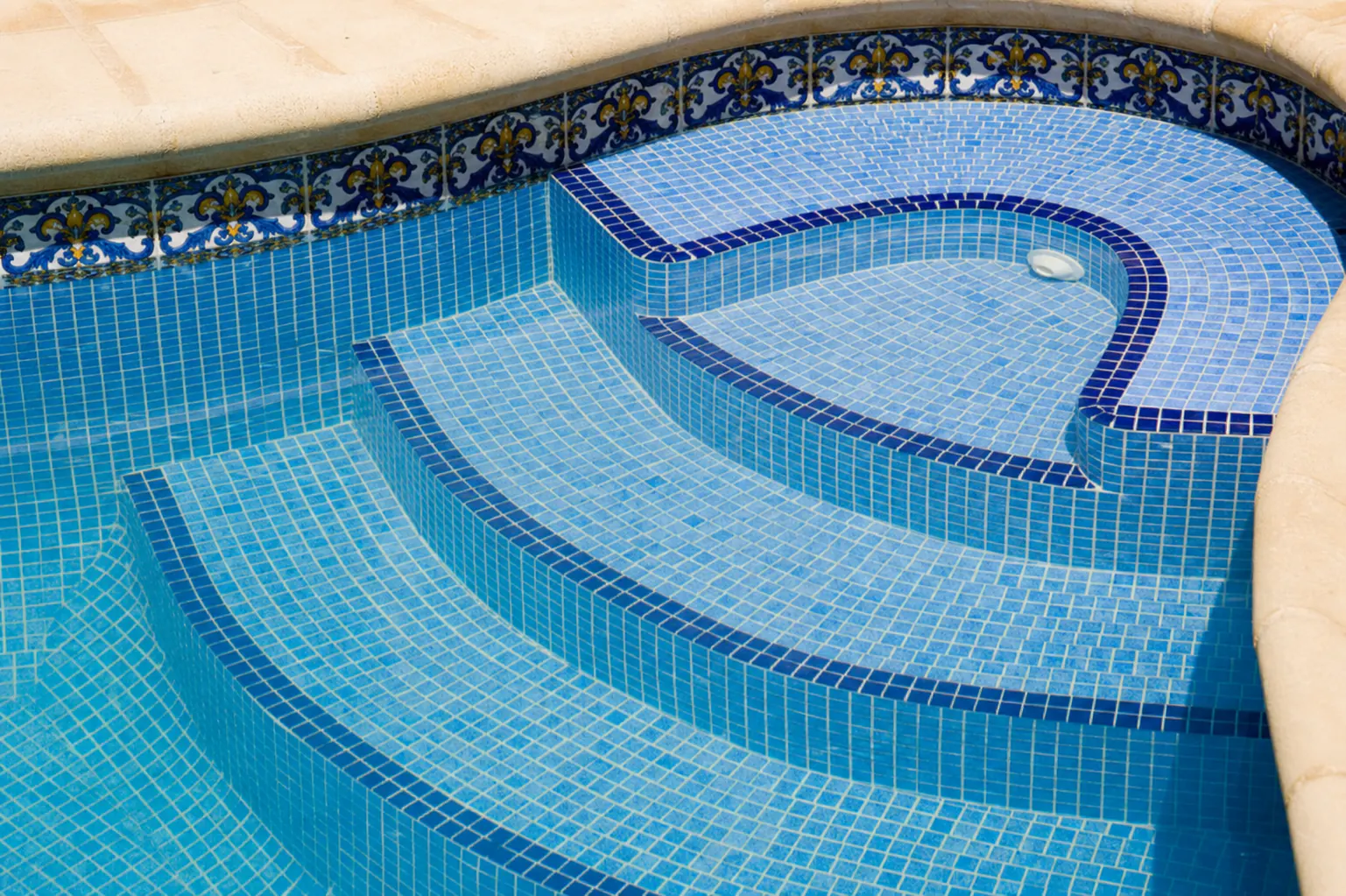 Escada curva e banco de piscina revestidos com pastilhas azuis