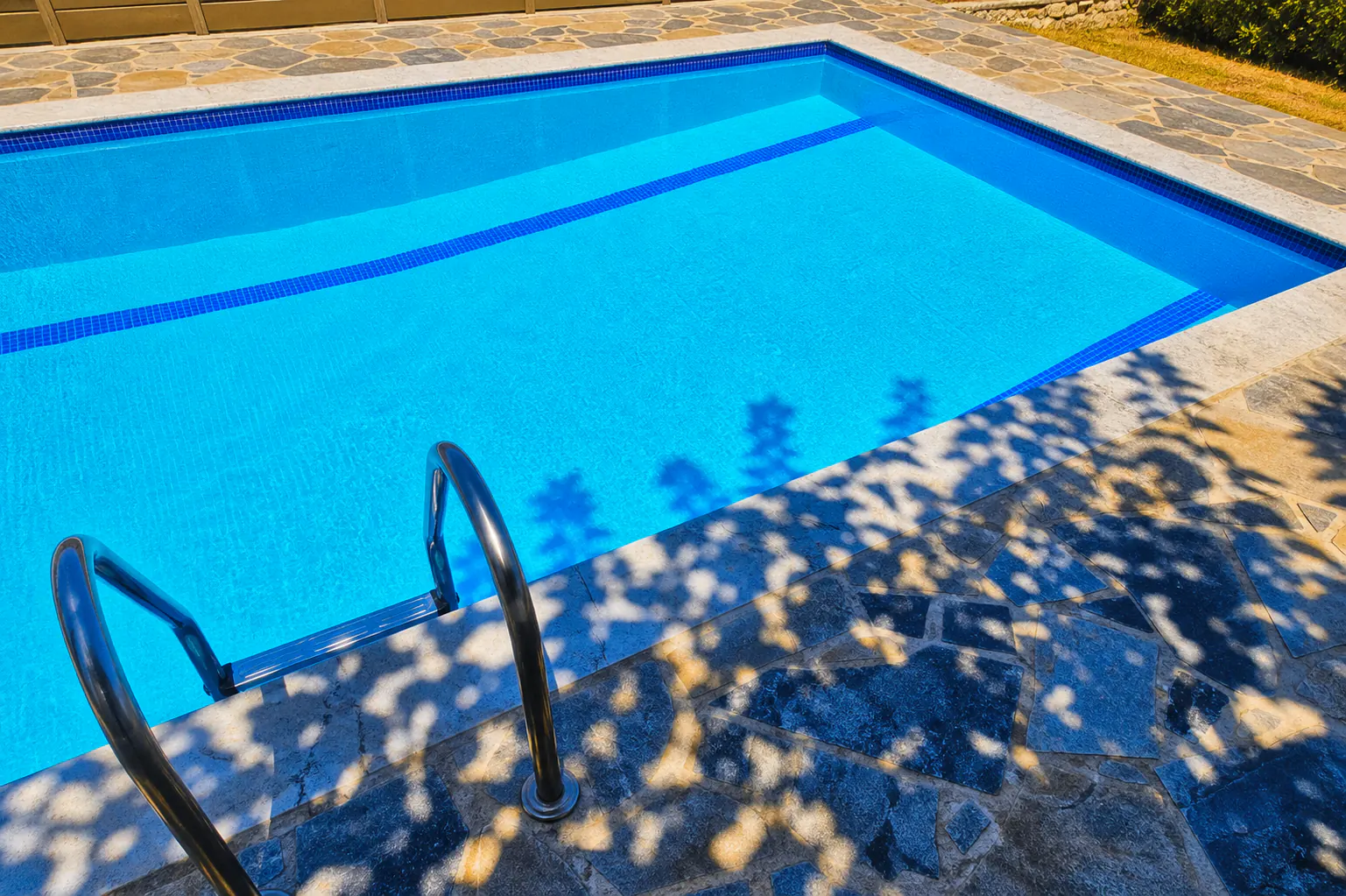 Piscina reformada com água cristalina e deck externo revestido em pedra