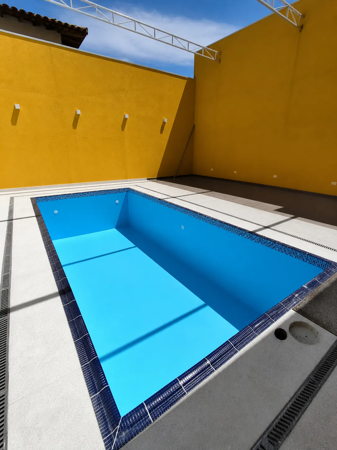 Piscina vazia reformada com pintura azul e acabamento em pastilhas