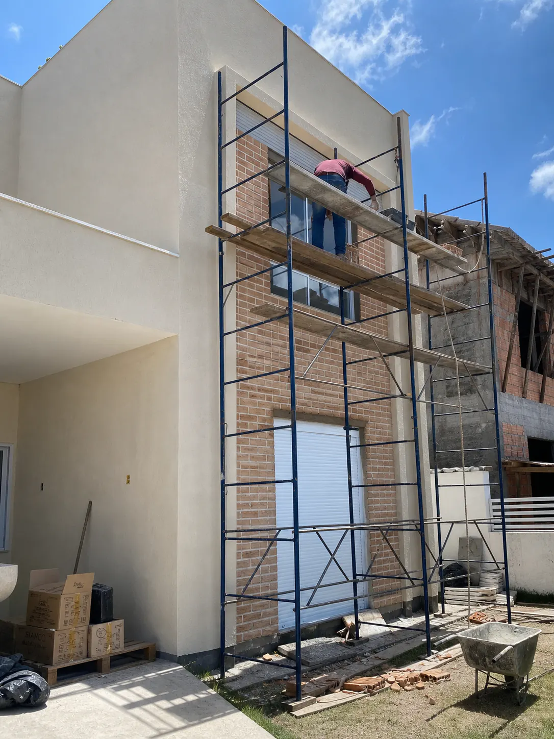Fachada residencial em reforma com andaimes e aplicação de revestimento