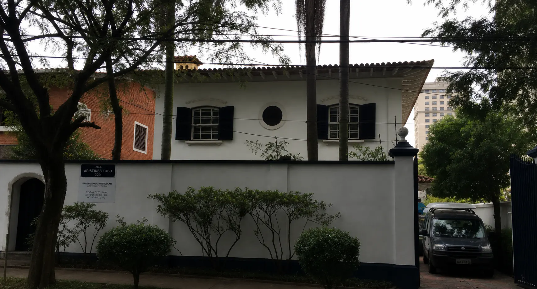 Fachada de residência restaurada com pintura clara e esquadrias escuras