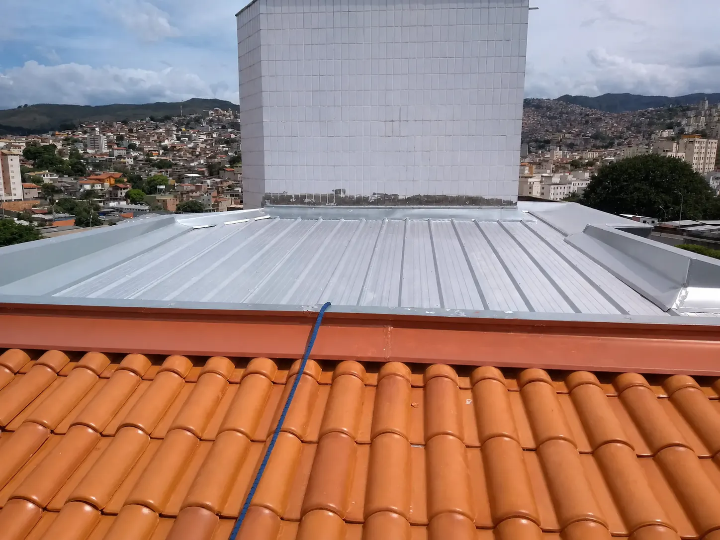 Cobertura metálica reformada junto a telhado cerâmico em apartamento