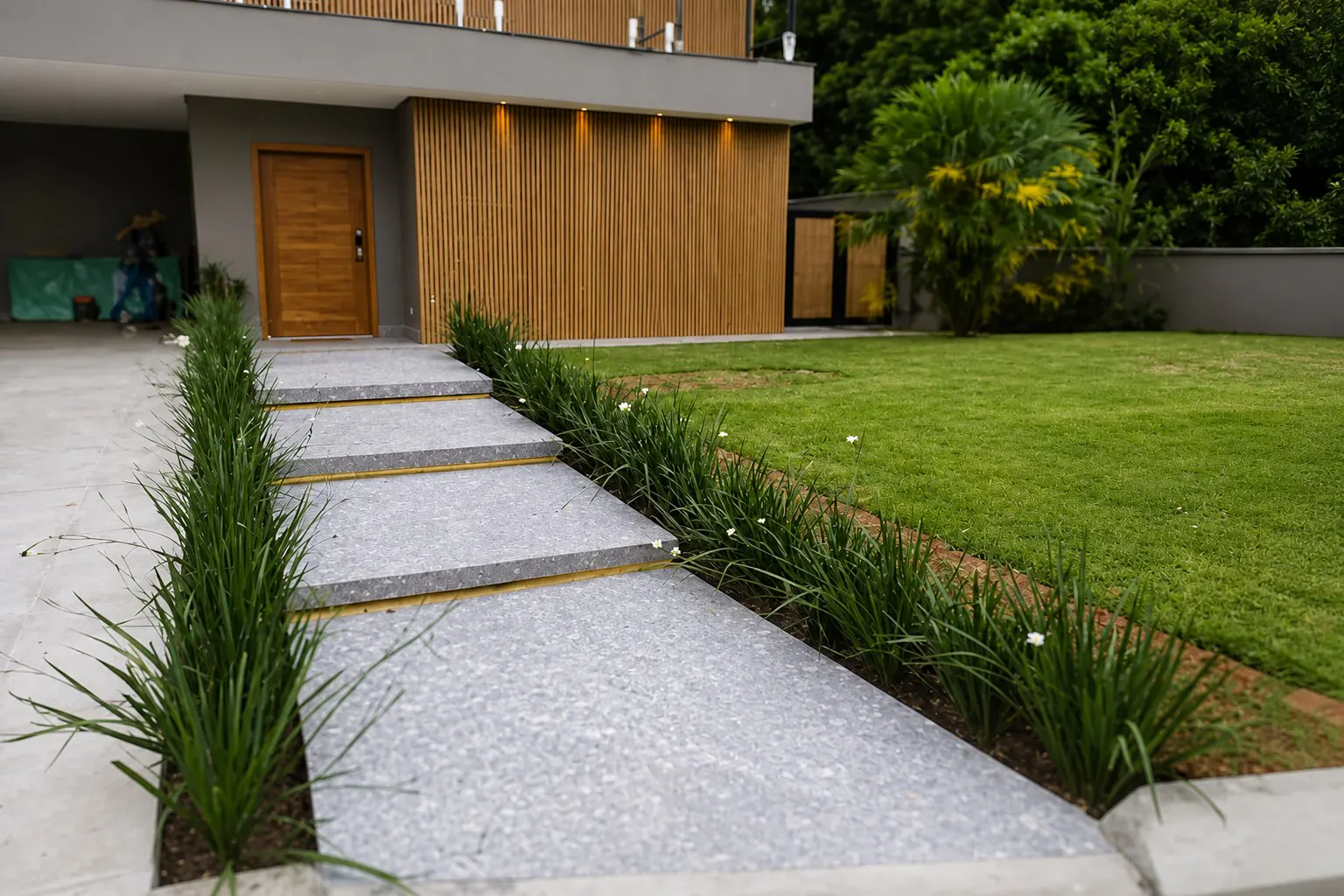 Entrada de residencia reformada com caminho de pedra e jardim