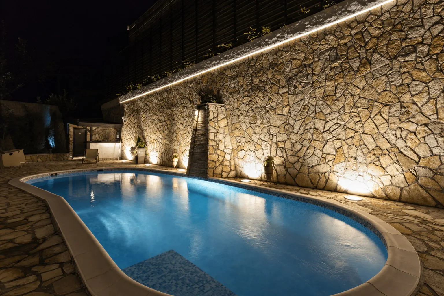 Piscina reformada com iluminacao noturna e revestimento em pedra